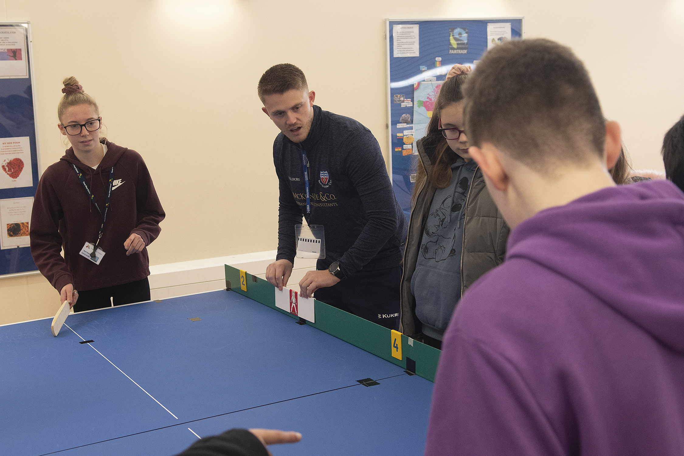 Cricket coach with pupils playing table cricket